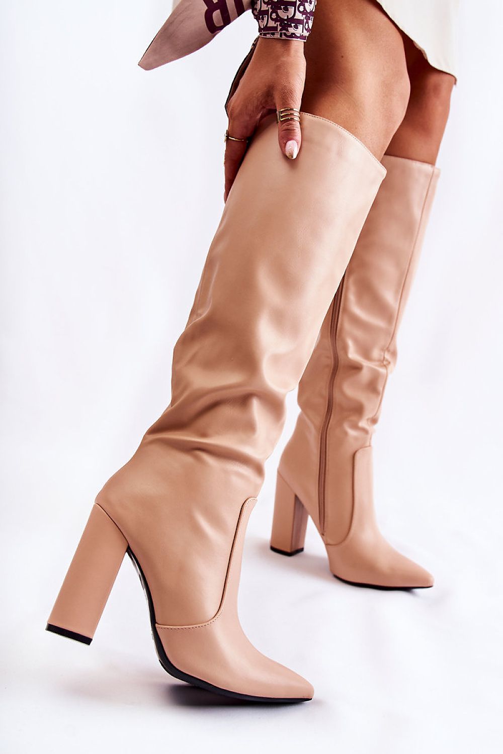 Beige knee-high boots being worn on a white background