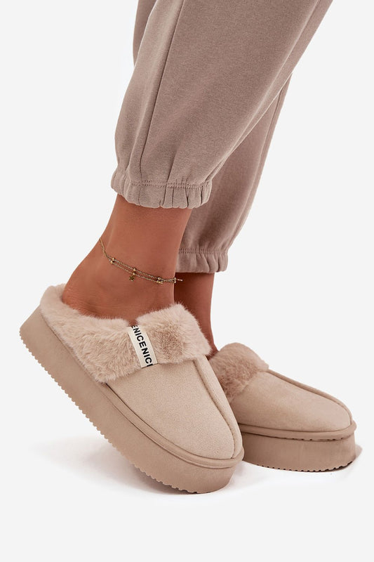 Beige slippers with fluffy trim worn by a person on a white background