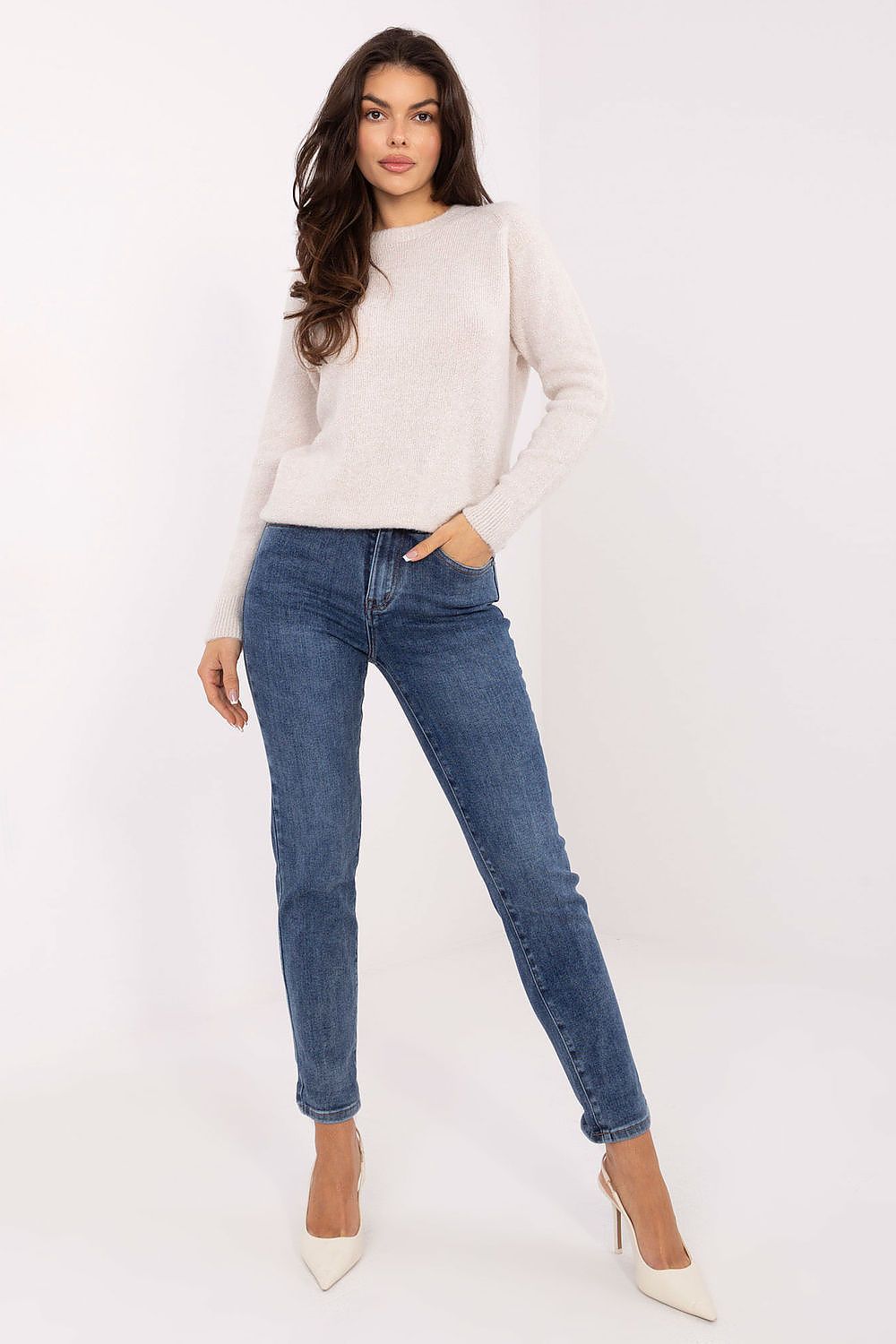 Woman wearing a white sweater and blue jeans on a white background