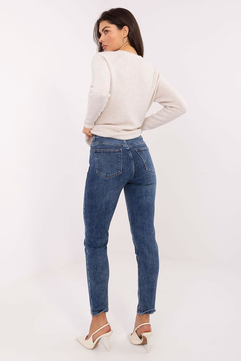 Woman wearing a white sweater and blue jeans on a white background