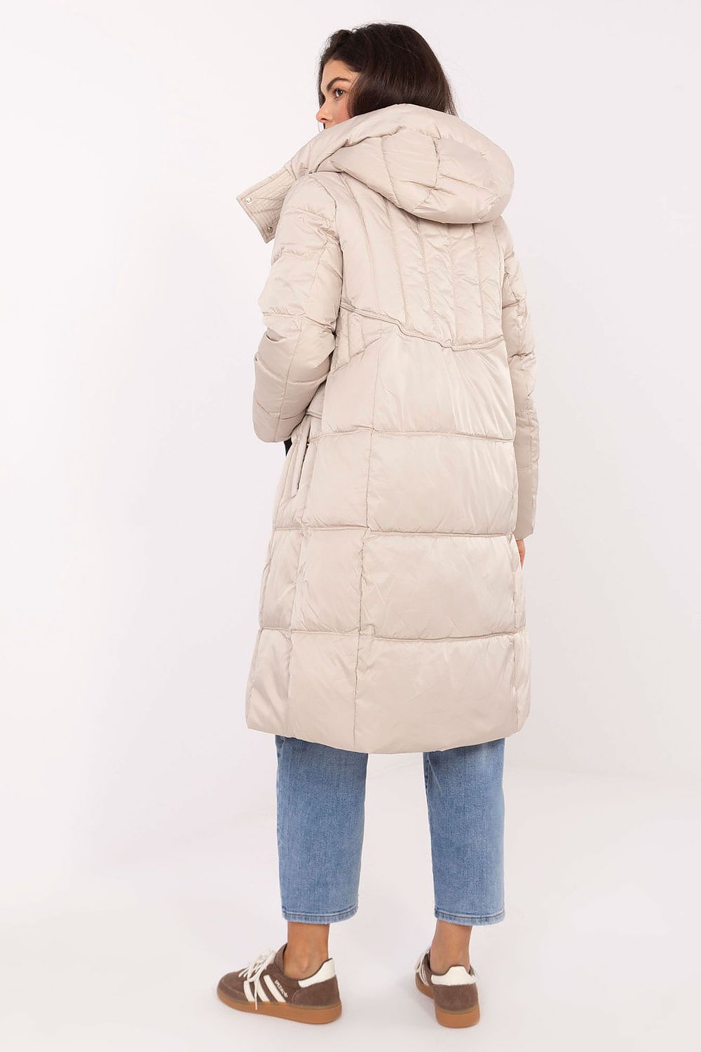 Person wearing a long beige puffer coat on a white background