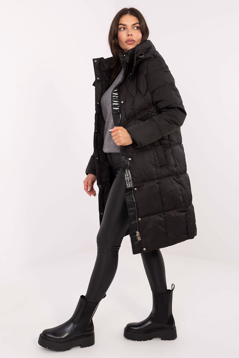 Woman wearing a long black puffer coat on a white background