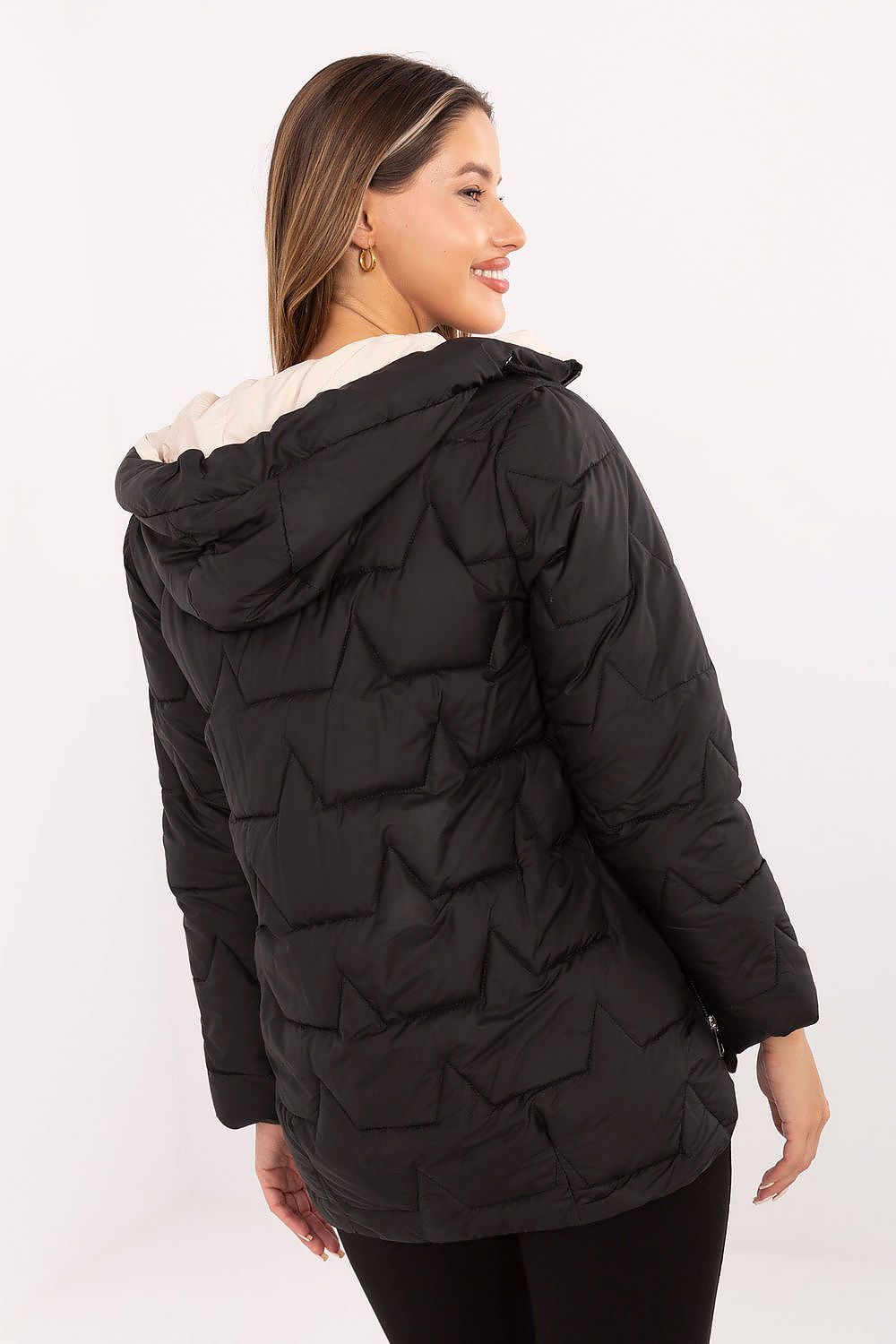Woman wearing a black quilted jacket with a hood on a white background