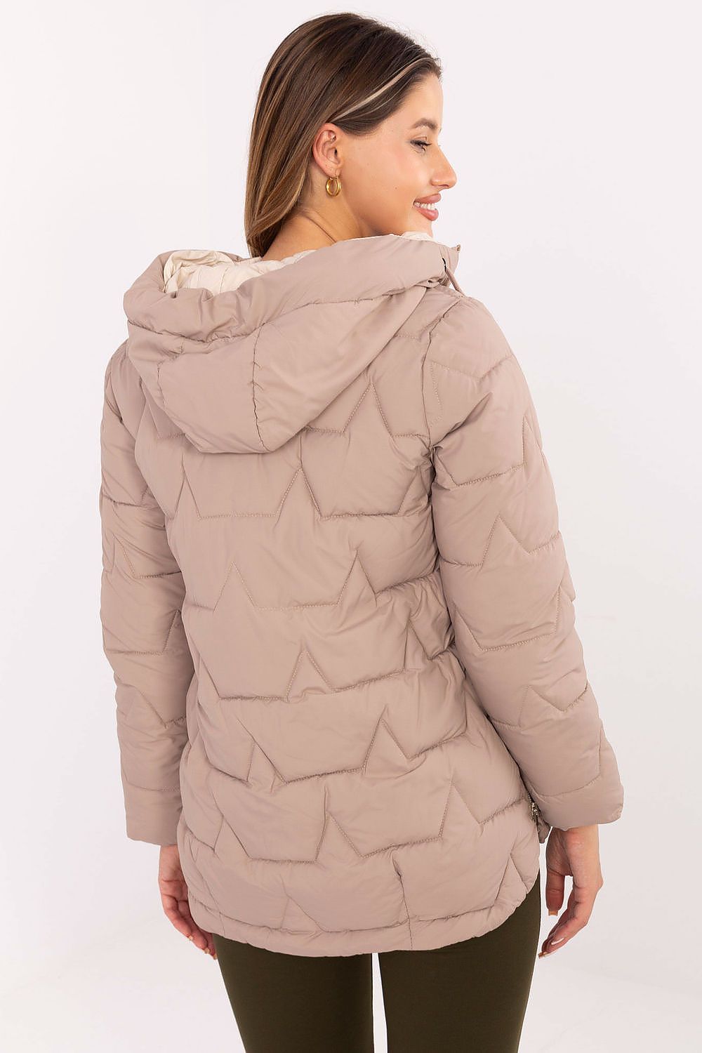 Woman wearing a beige quilted jacket on a white background