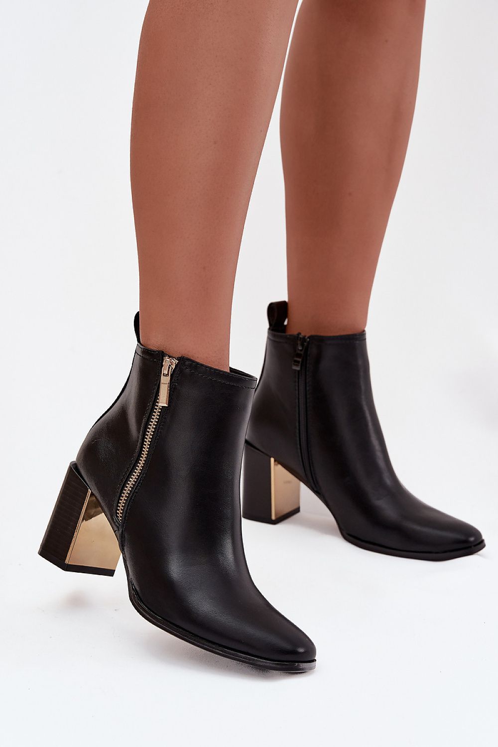 Black ankle boots with block heels worn by a person on a white background