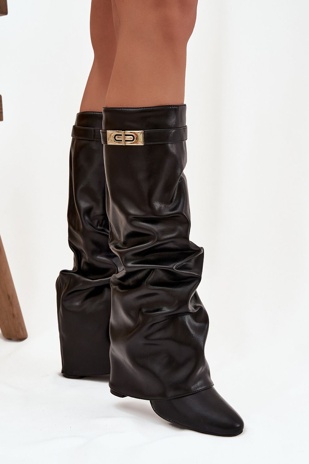 Black leather gaiters with a gold buckle on a white background
