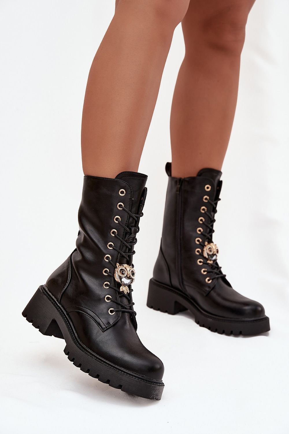 Black leather boots with decorative elements on a white background