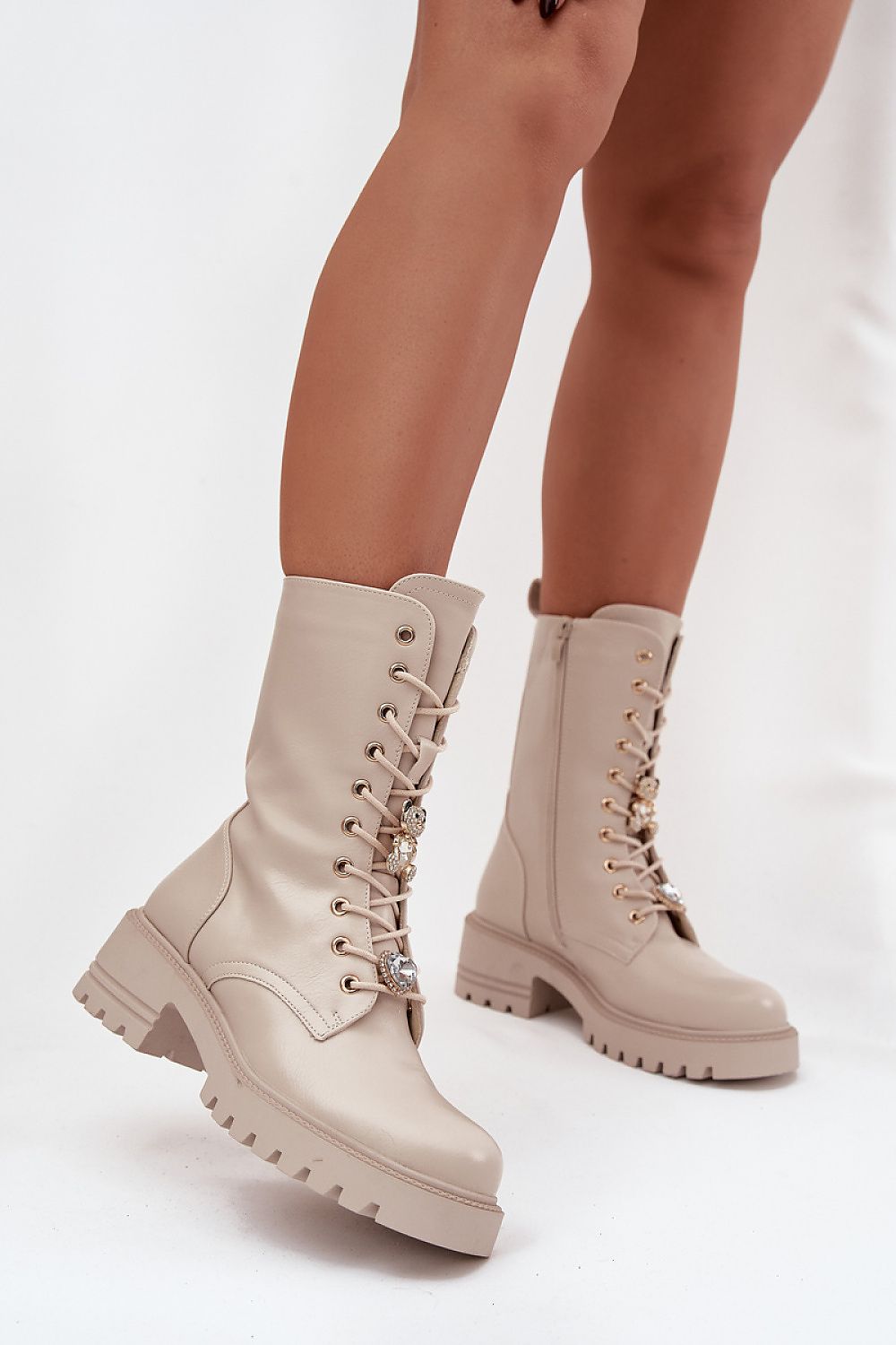 Beige combat boots worn by a person on a white background