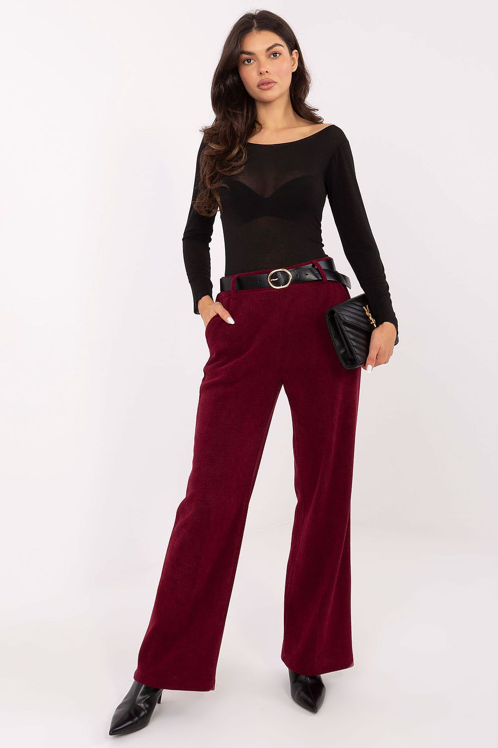 Woman wearing a black top and red pants with a white background