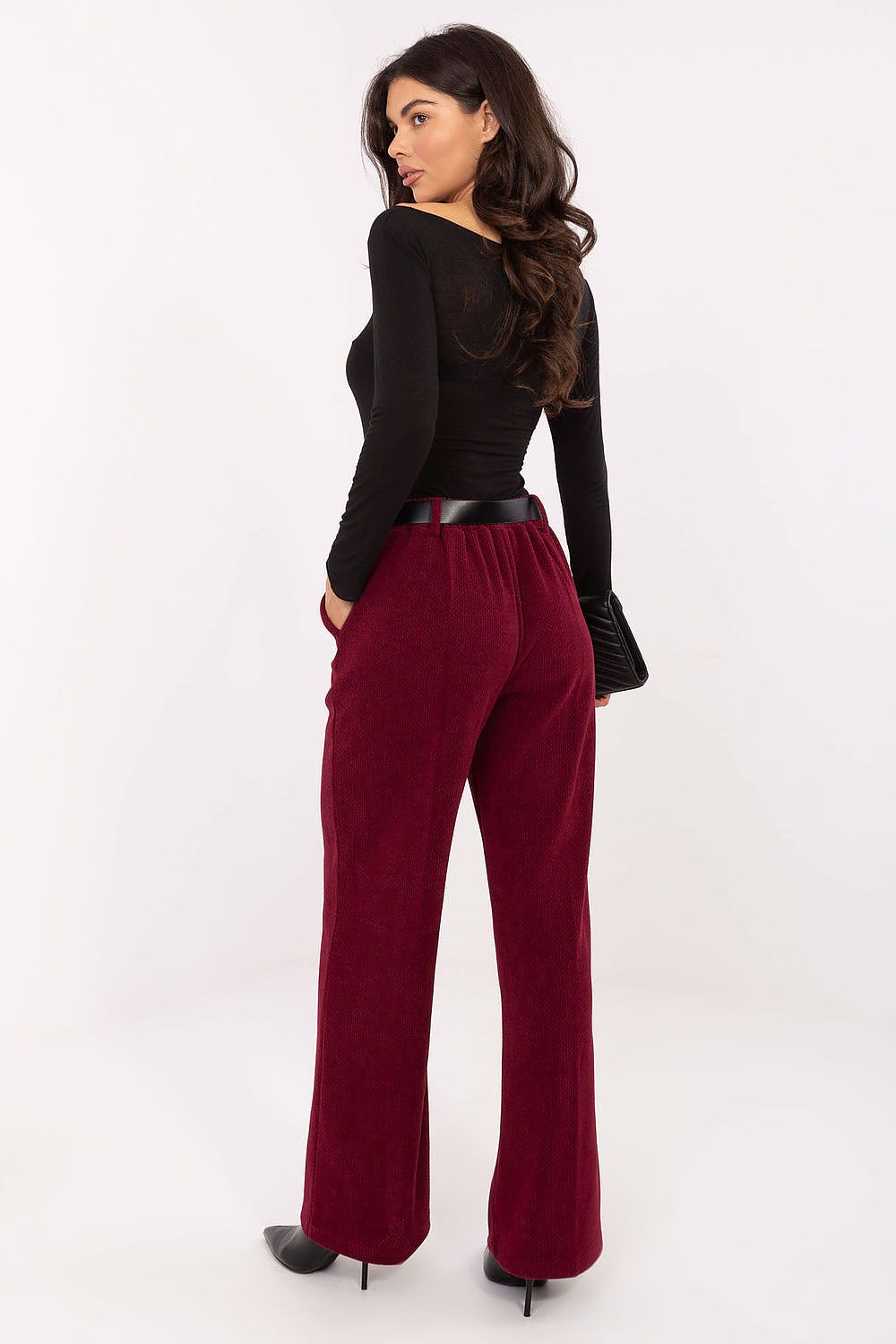 Woman wearing red pants and a black top on a white background