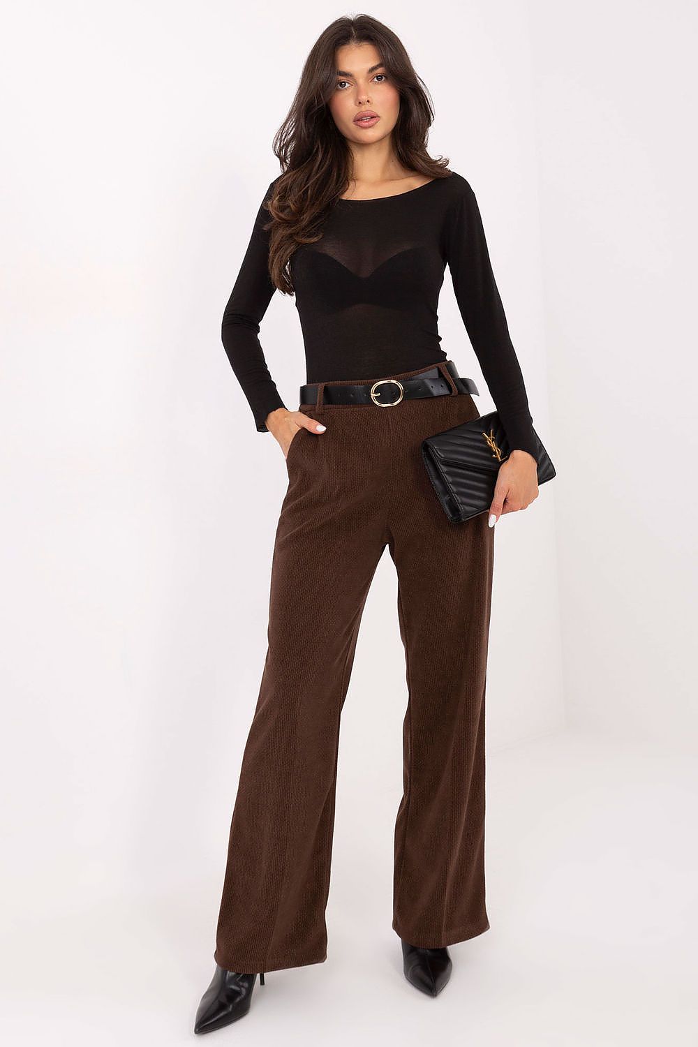Woman wearing a black top and brown pants with a white background