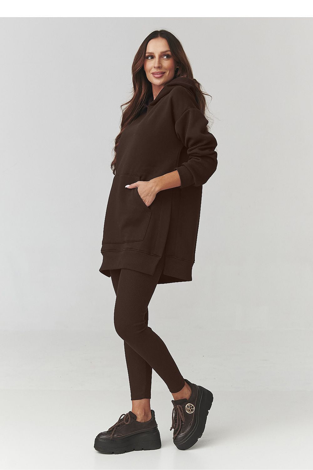 Woman wearing a brown hoodie and leggings on a white background