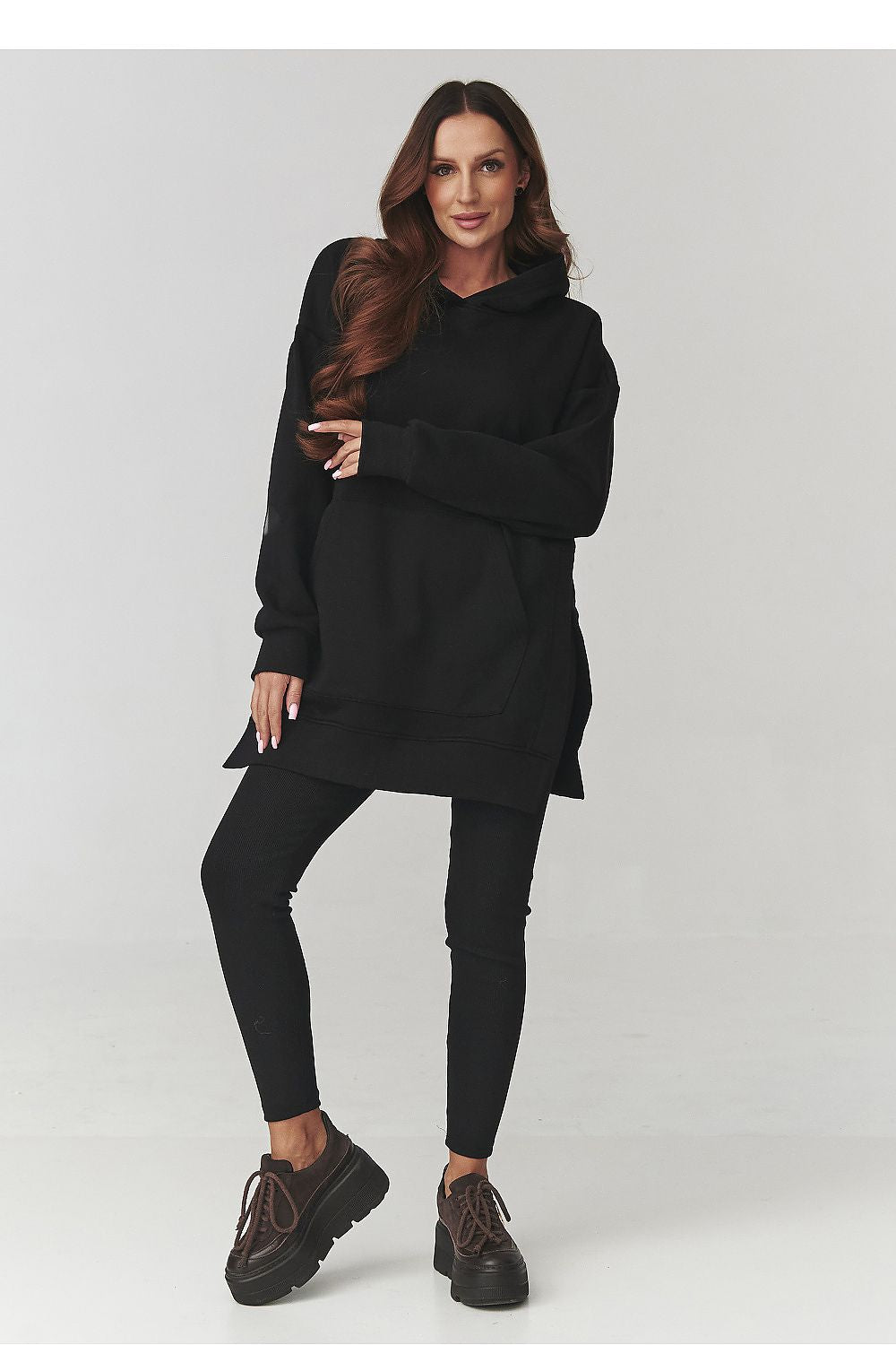 Woman wearing a black oversized sweater and leggings on a white background