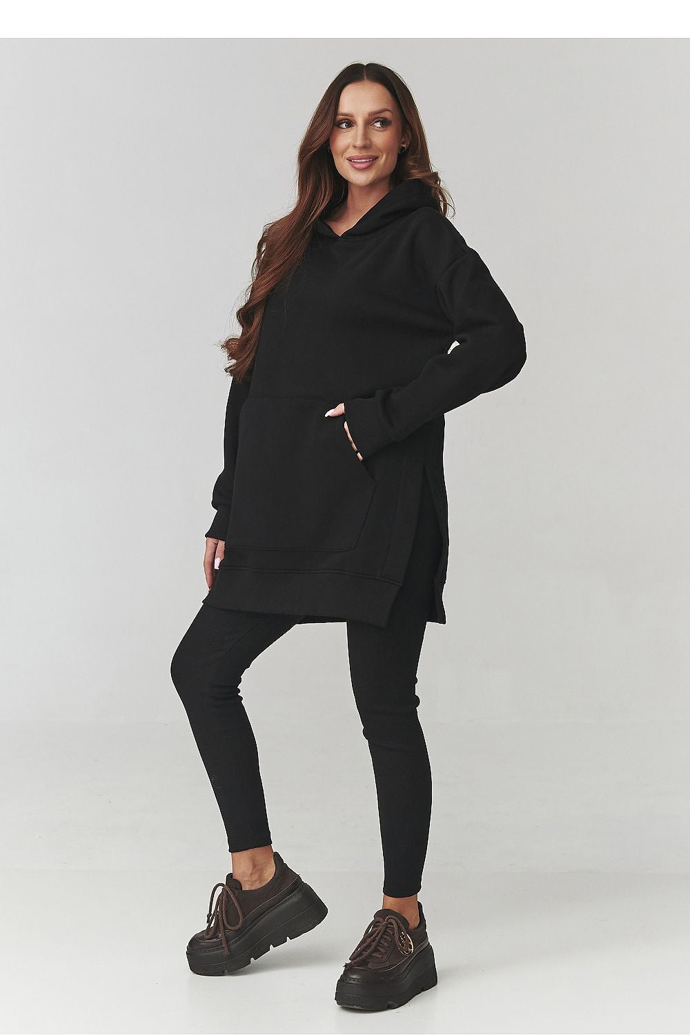Woman wearing a black hoodie and leggings on a white background