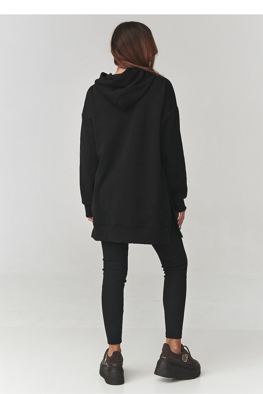 Person wearing a black hoodie and pants on a white background