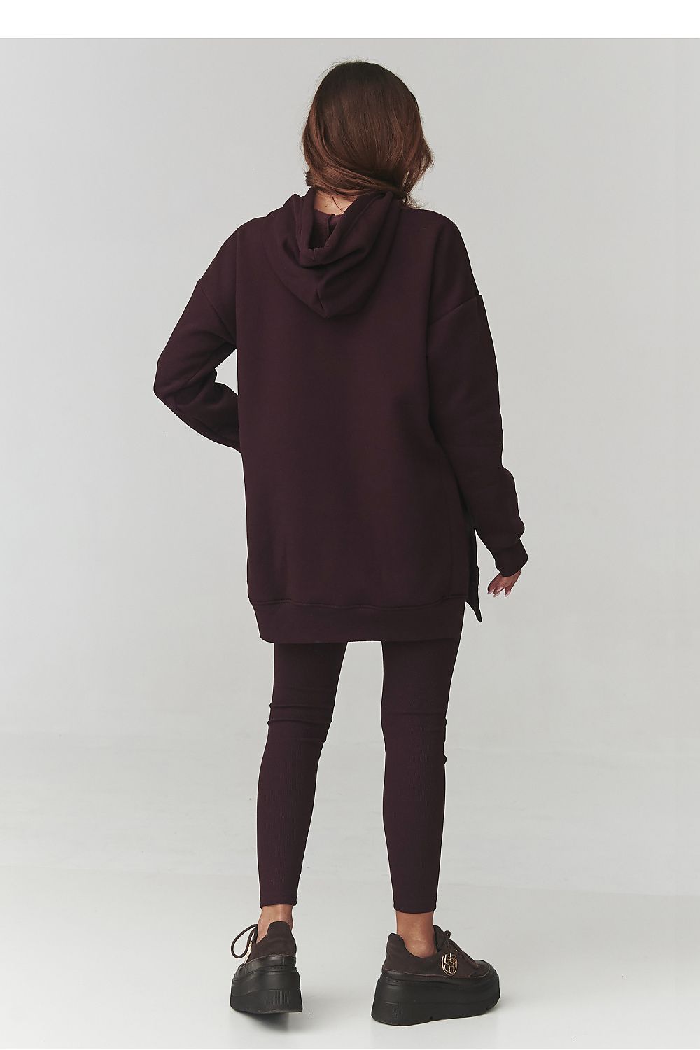 Person wearing a dark hoodie and leggings on a white background