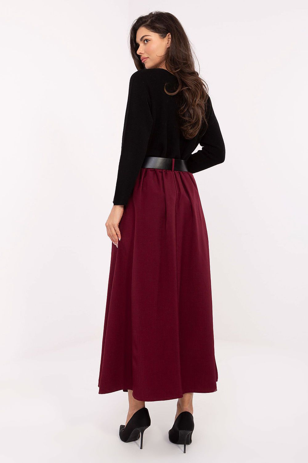 Woman wearing a black top and burgundy skirt on a white background