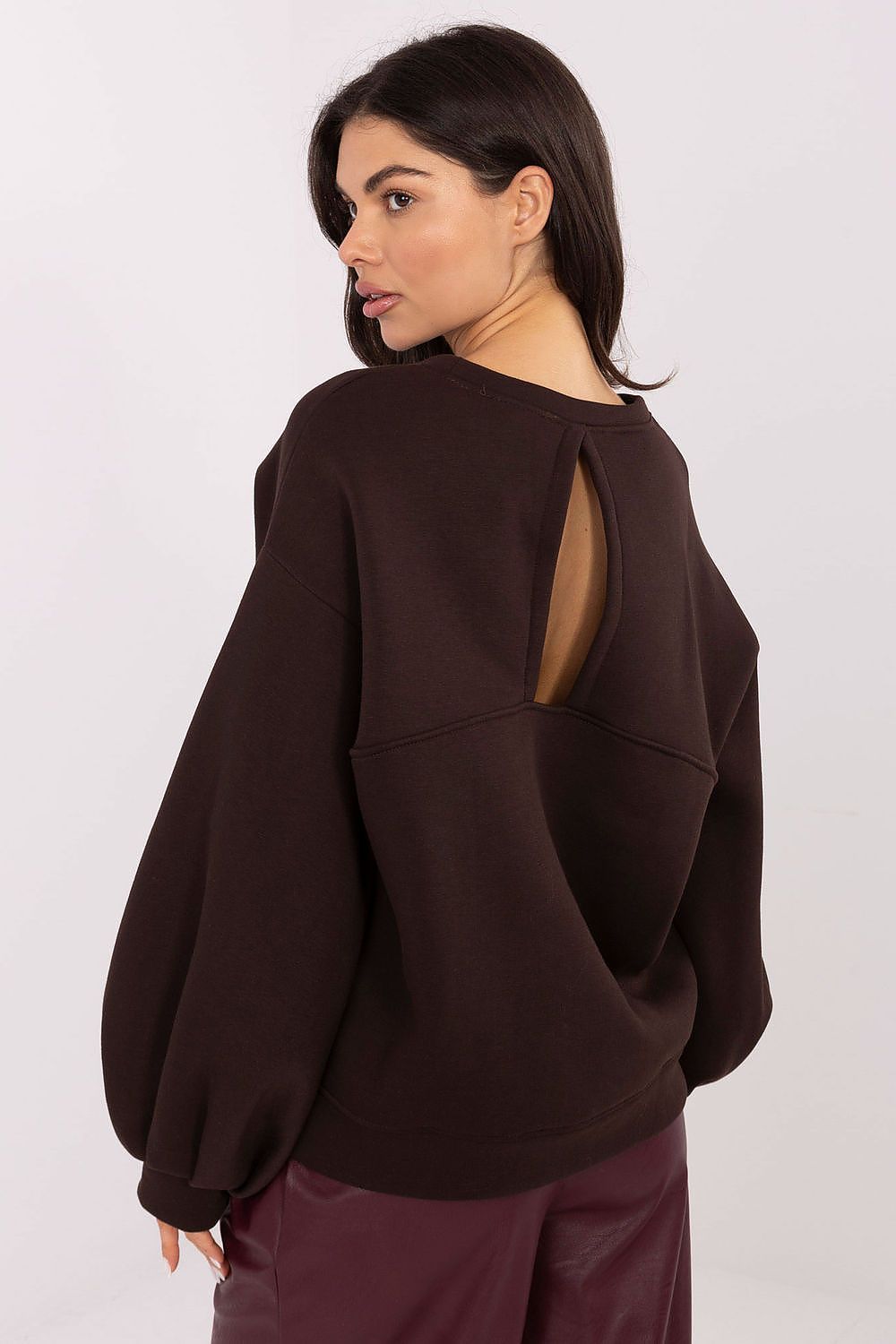 Woman wearing a brown sweatshirt with cut-out back design on a white background