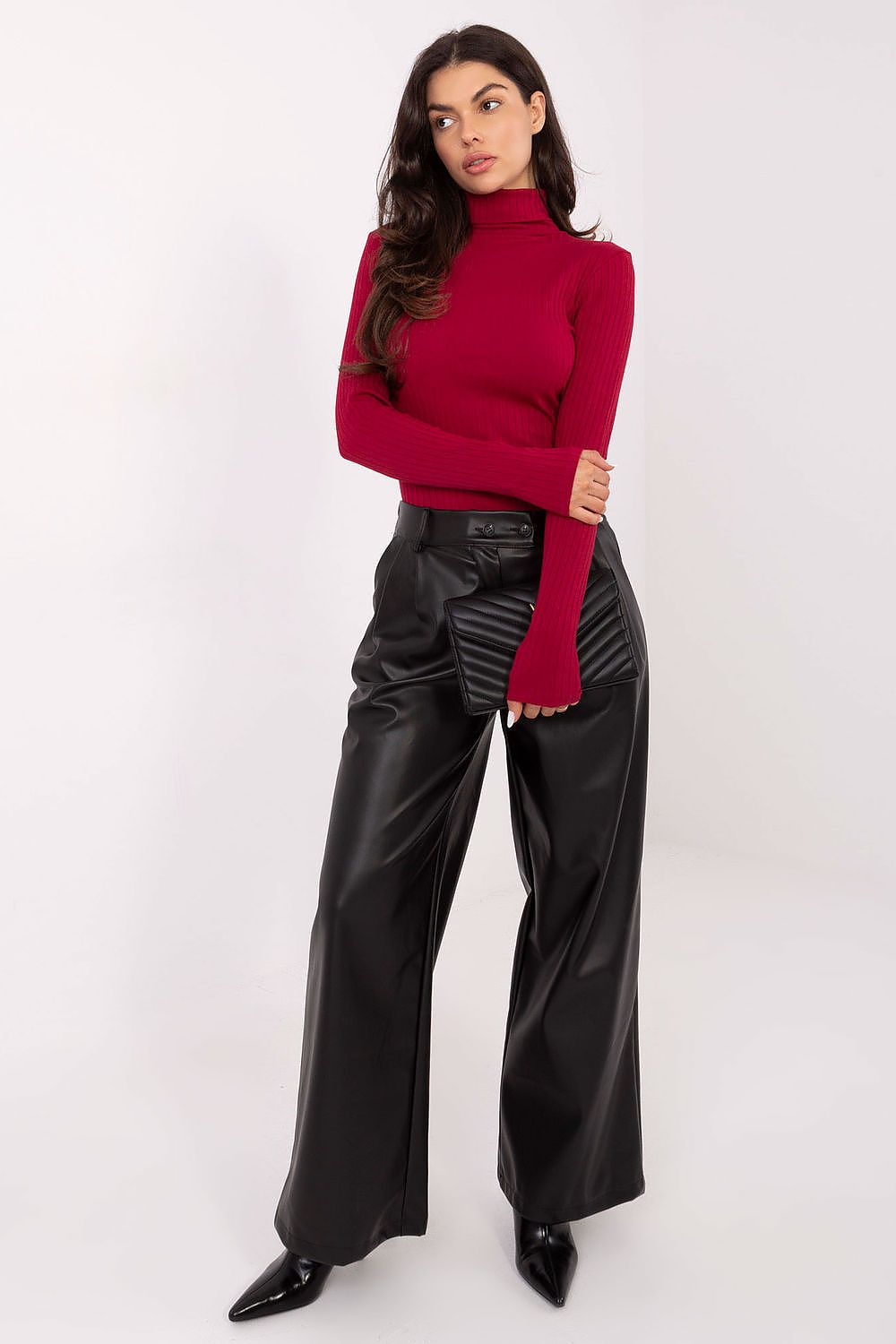 Woman wearing a red sweater and black leather pants on a white background