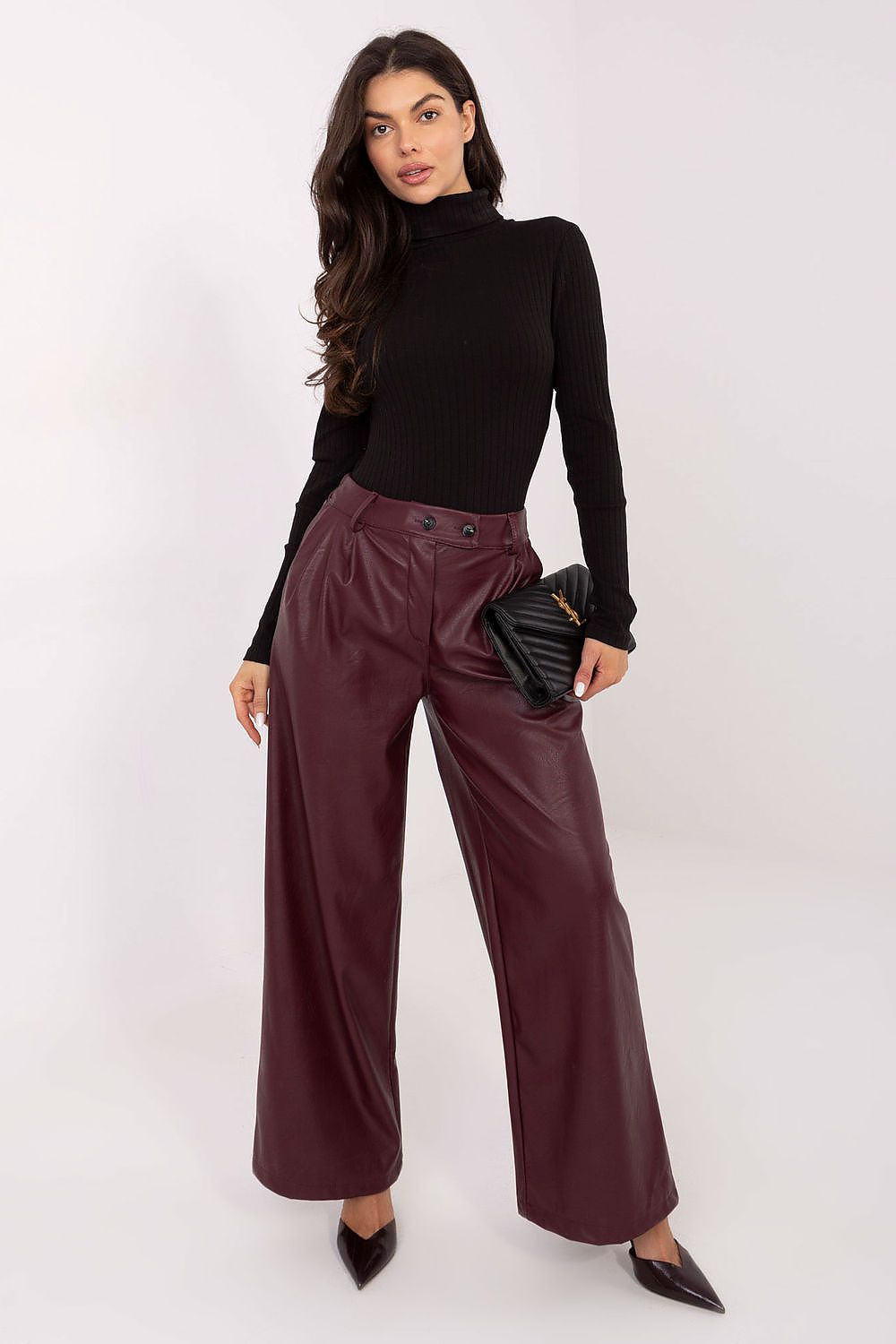 Woman wearing a black turtleneck and burgundy pants on a white background