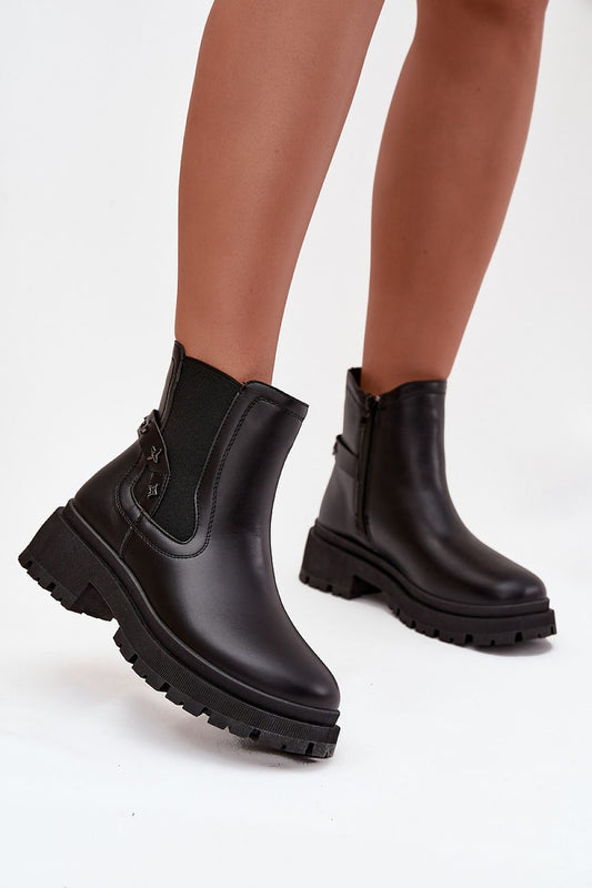 Black rubber boots worn by a person on a white background