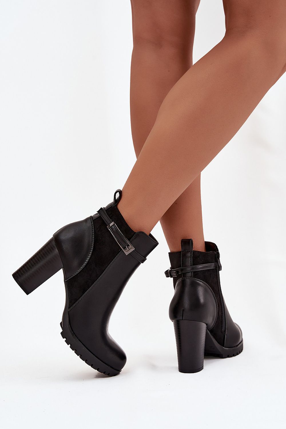 Black ankle boots worn by a person on a white background