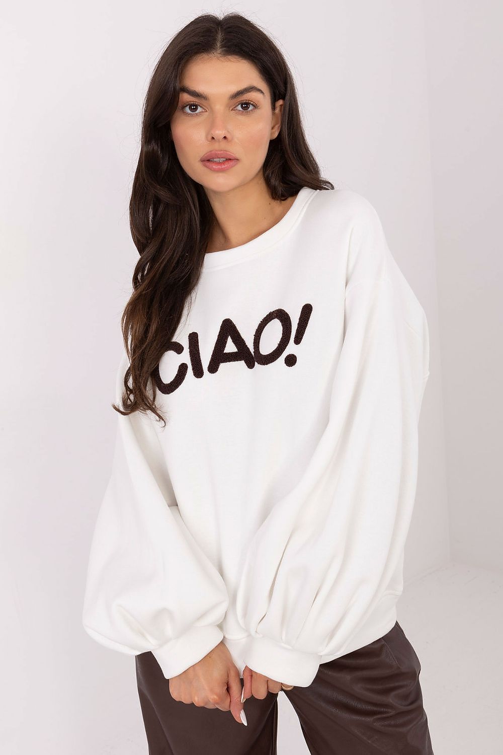 Woman wearing a white sweatshirt with 'CIAO!' text on a plain background