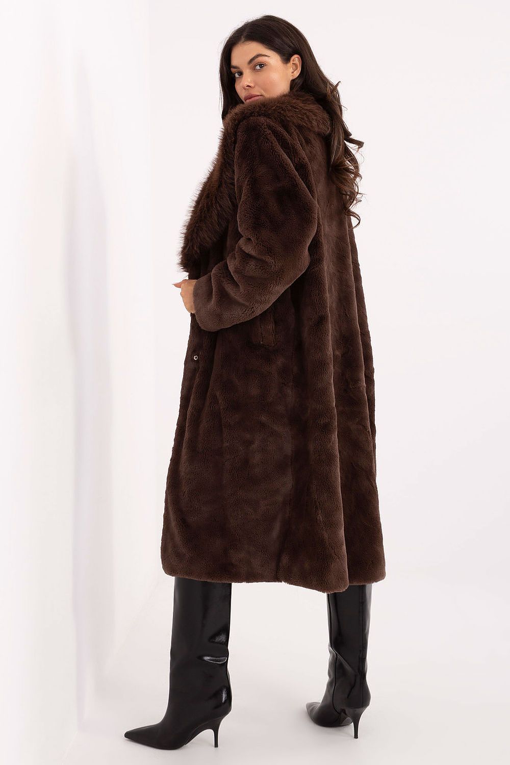Woman wearing a long brown fur coat on a white background