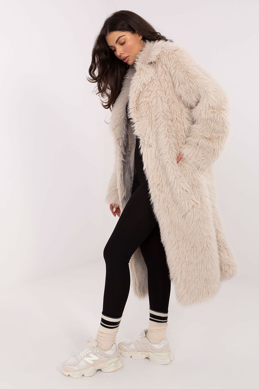 Woman wearing a long beige fur coat on a white background