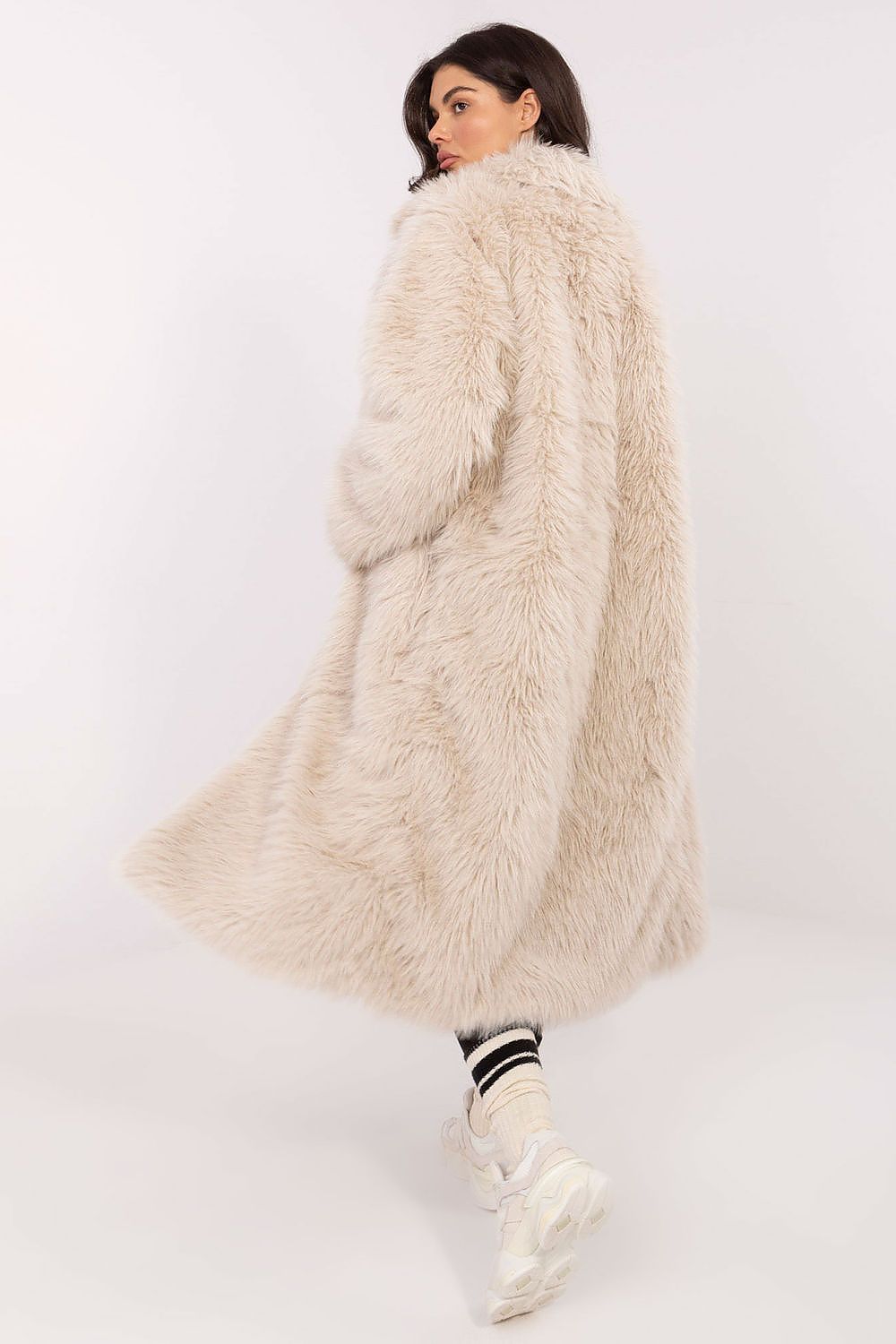 Woman wearing a long beige fur coat on a white background
