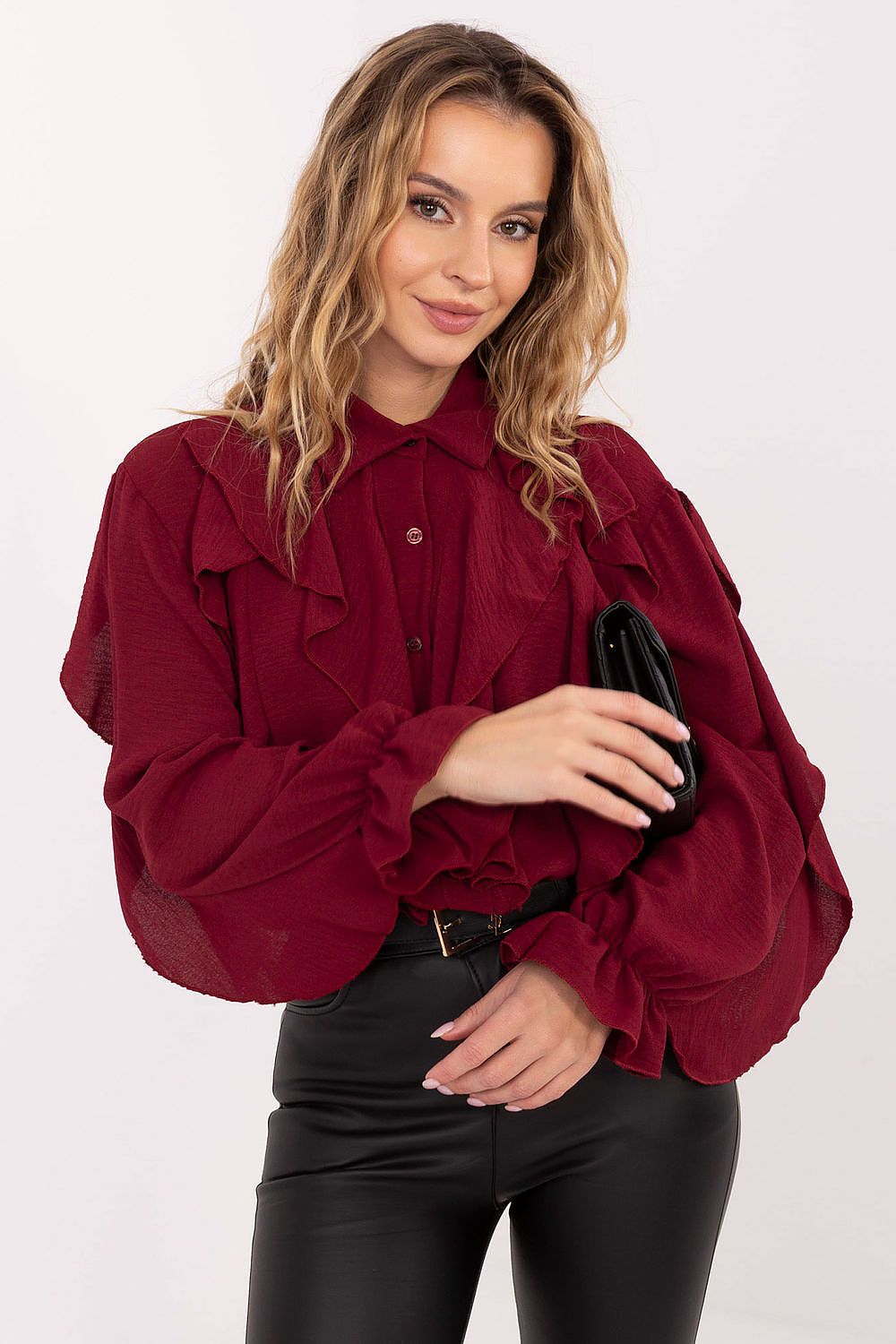 Woman wearing a burgundy blouse with ruffled sleeves on a white background