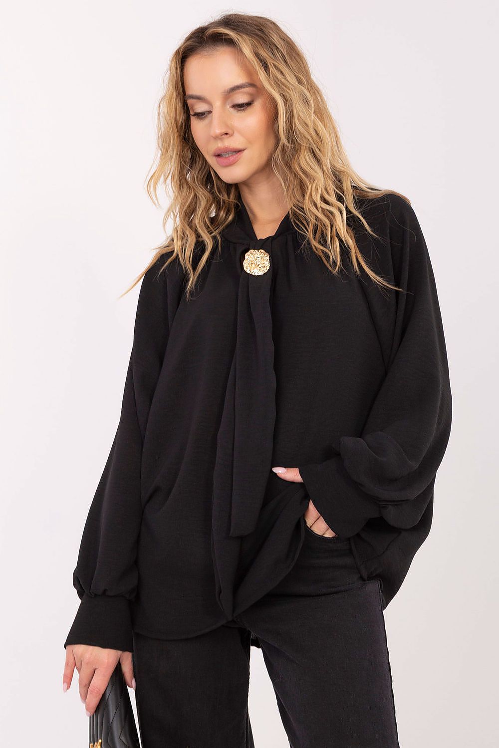 Woman wearing a black outfit with a large bow tie against a white background