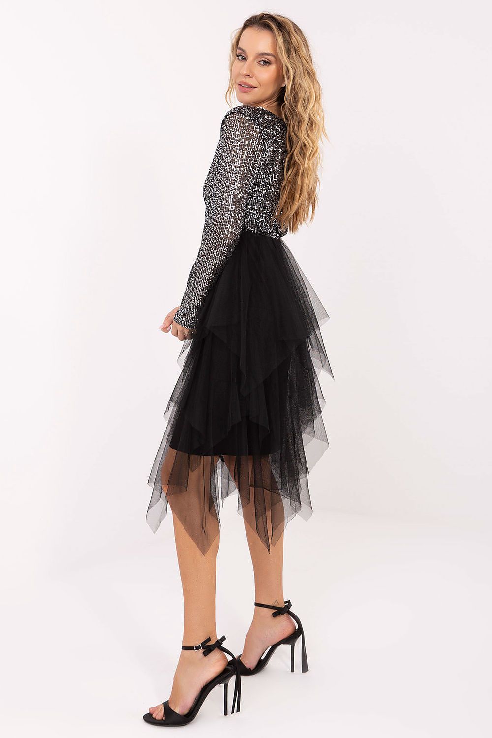Woman wearing a black tulle skirt with a silver sequin top on a white background