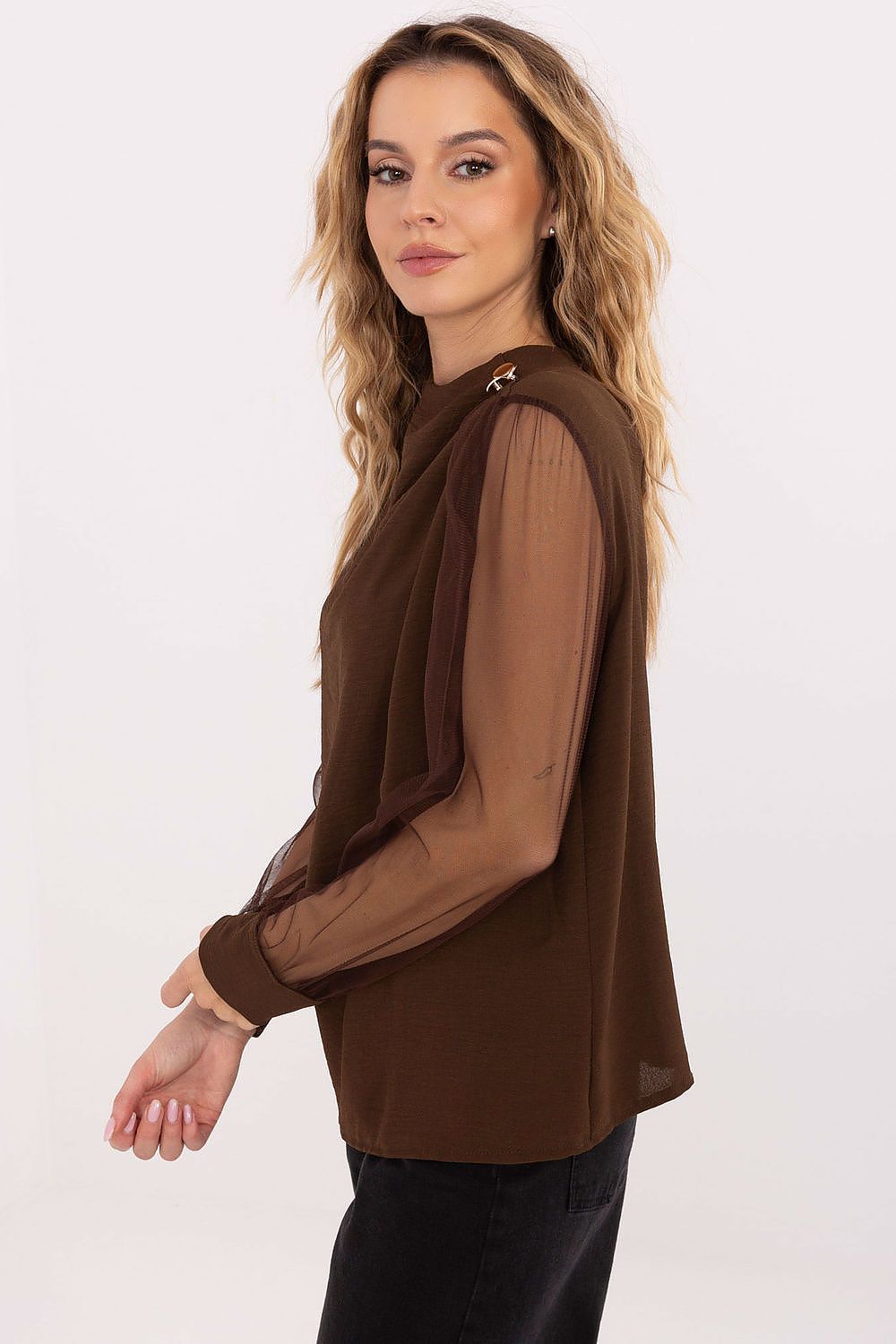 Woman wearing a brown blouse with sheer sleeves on a white background