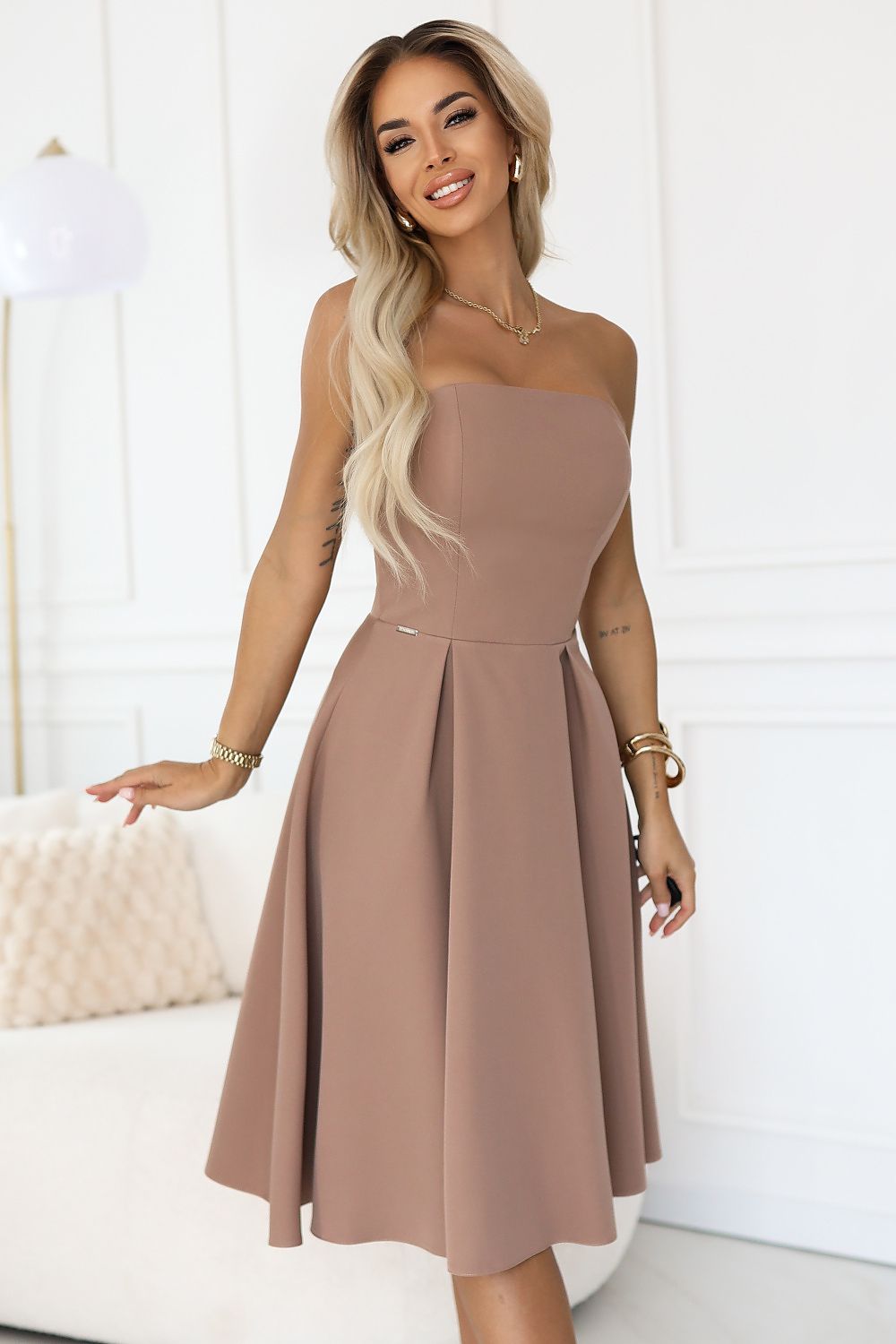 Woman wearing a strapless brown dress in a minimalistic setting