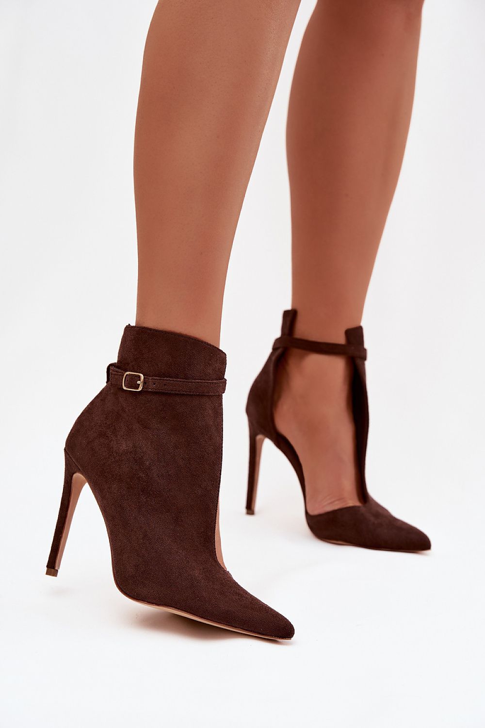 Brown high-heeled ankle boots worn with sheer leggings on a white background