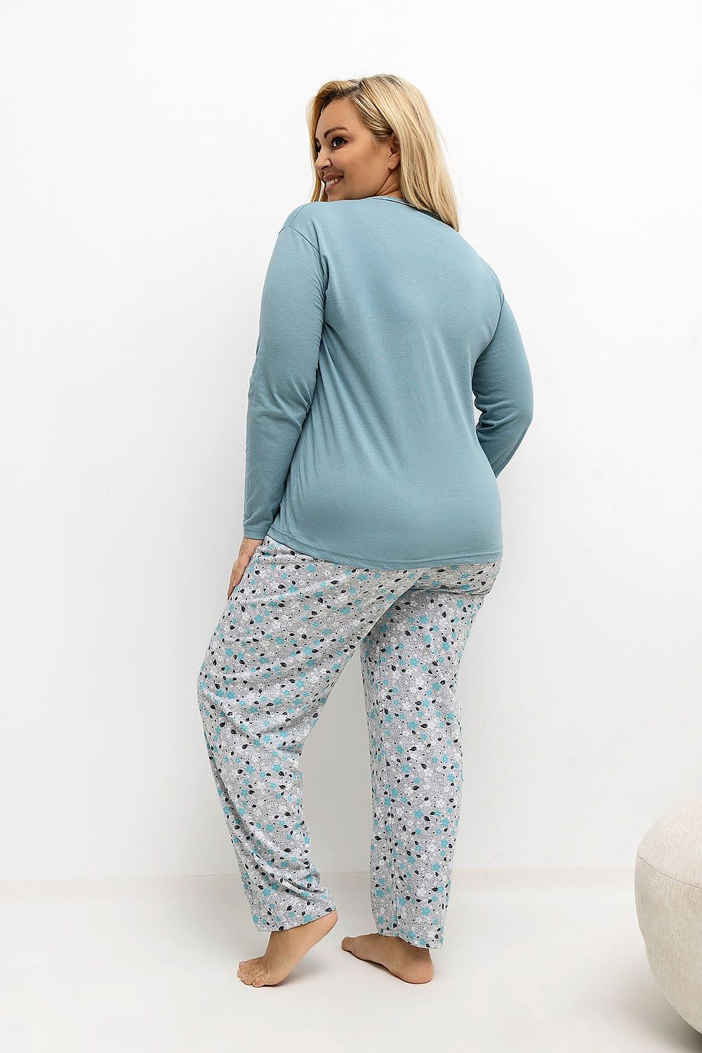 Woman wearing a blue top and patterned pants on a white background