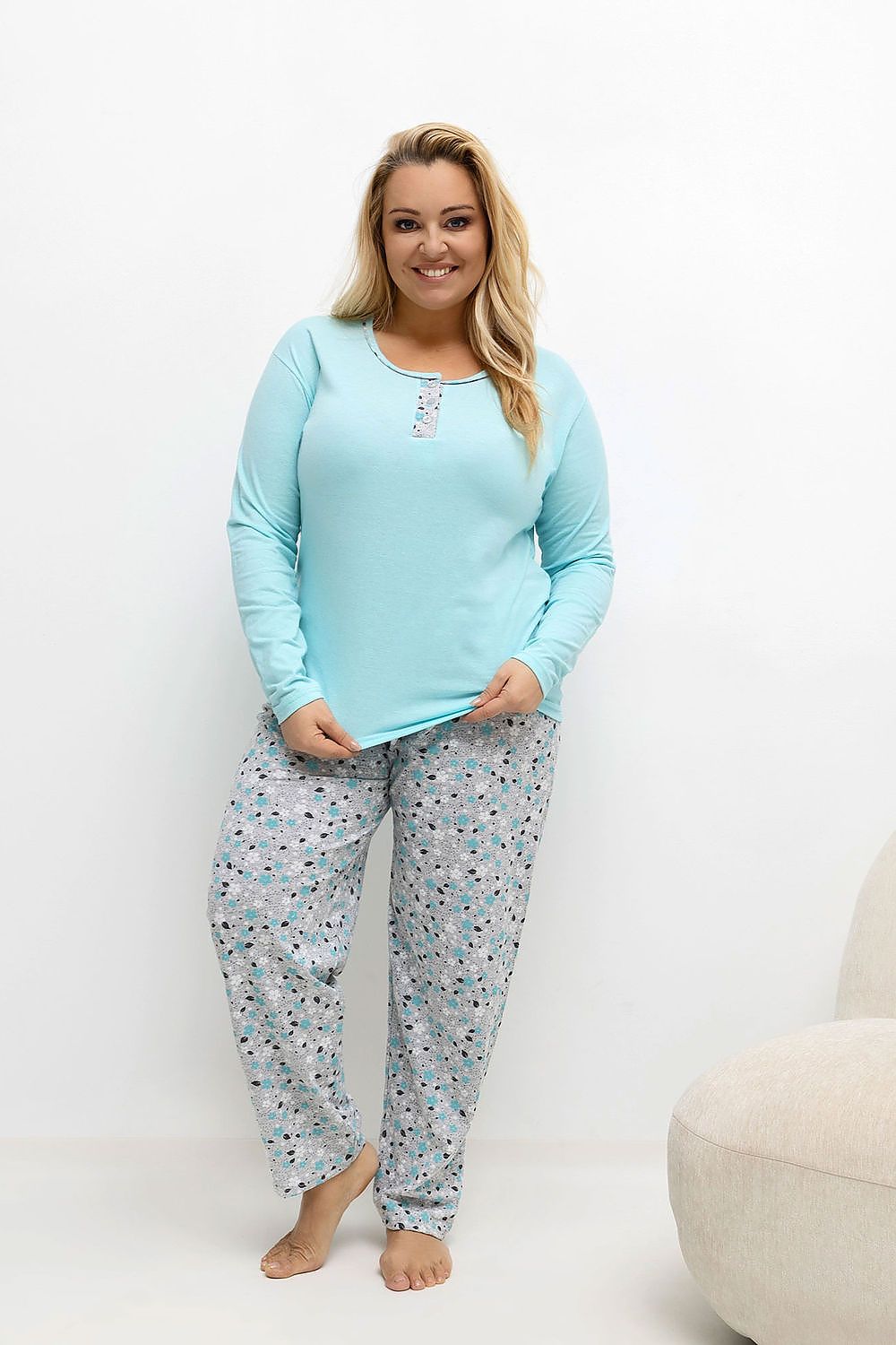 Woman wearing a light blue pajama top and patterned pants on a white background