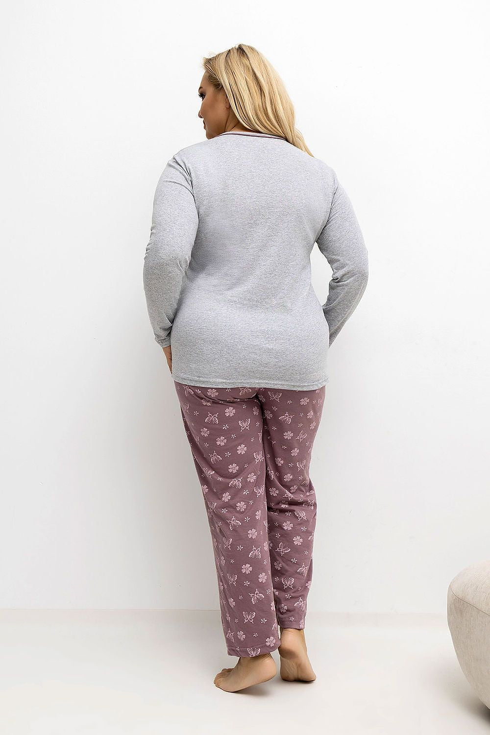 Person wearing a gray long-sleeve top and pink pajama pants with a floral pattern on a white background