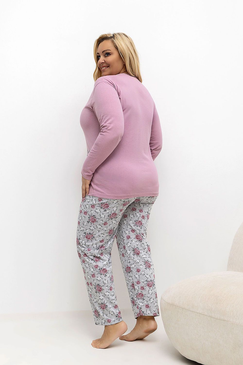 Woman wearing a pink top and floral pants on a white background