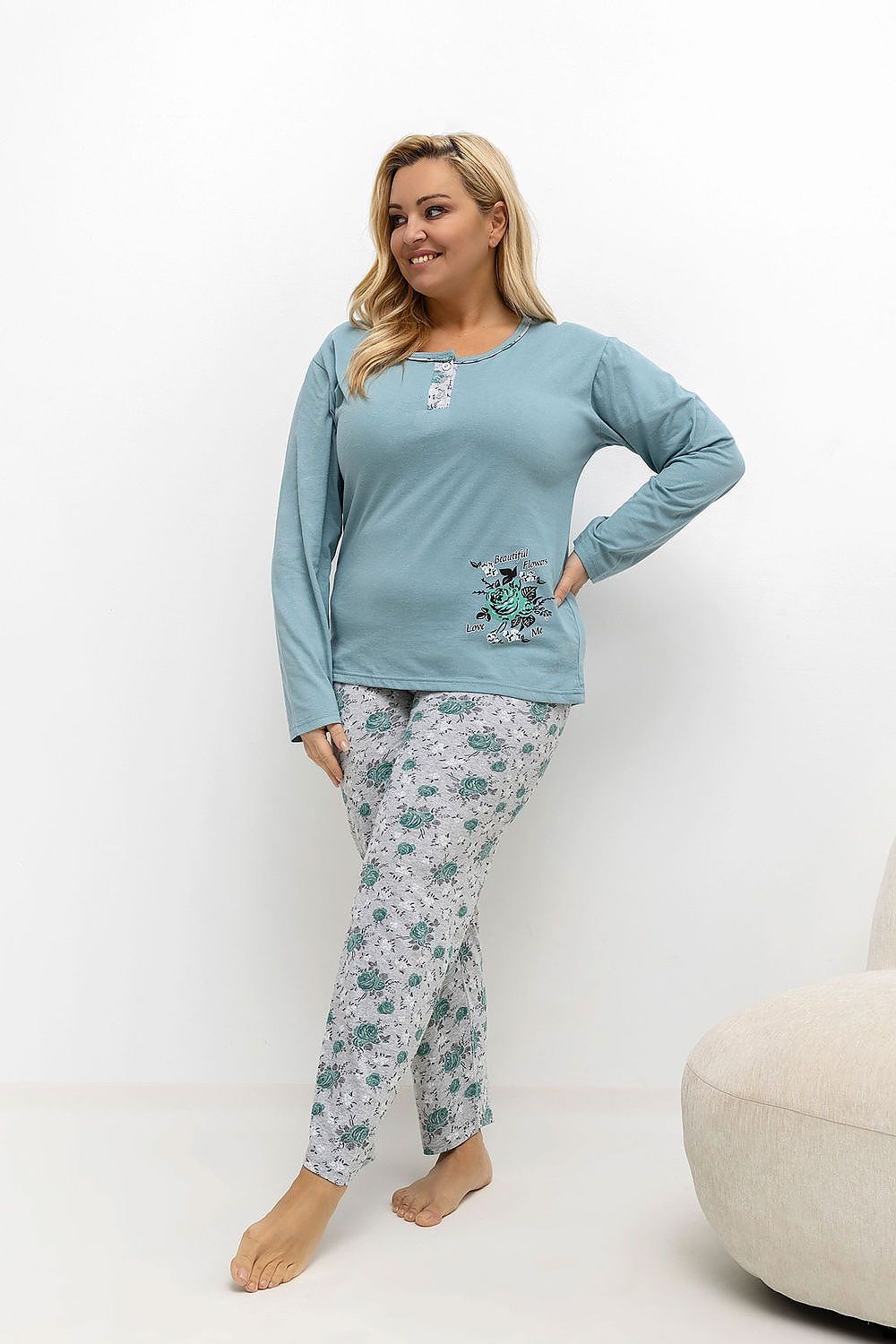 Woman wearing a light blue pajama top and floral pants on a white background