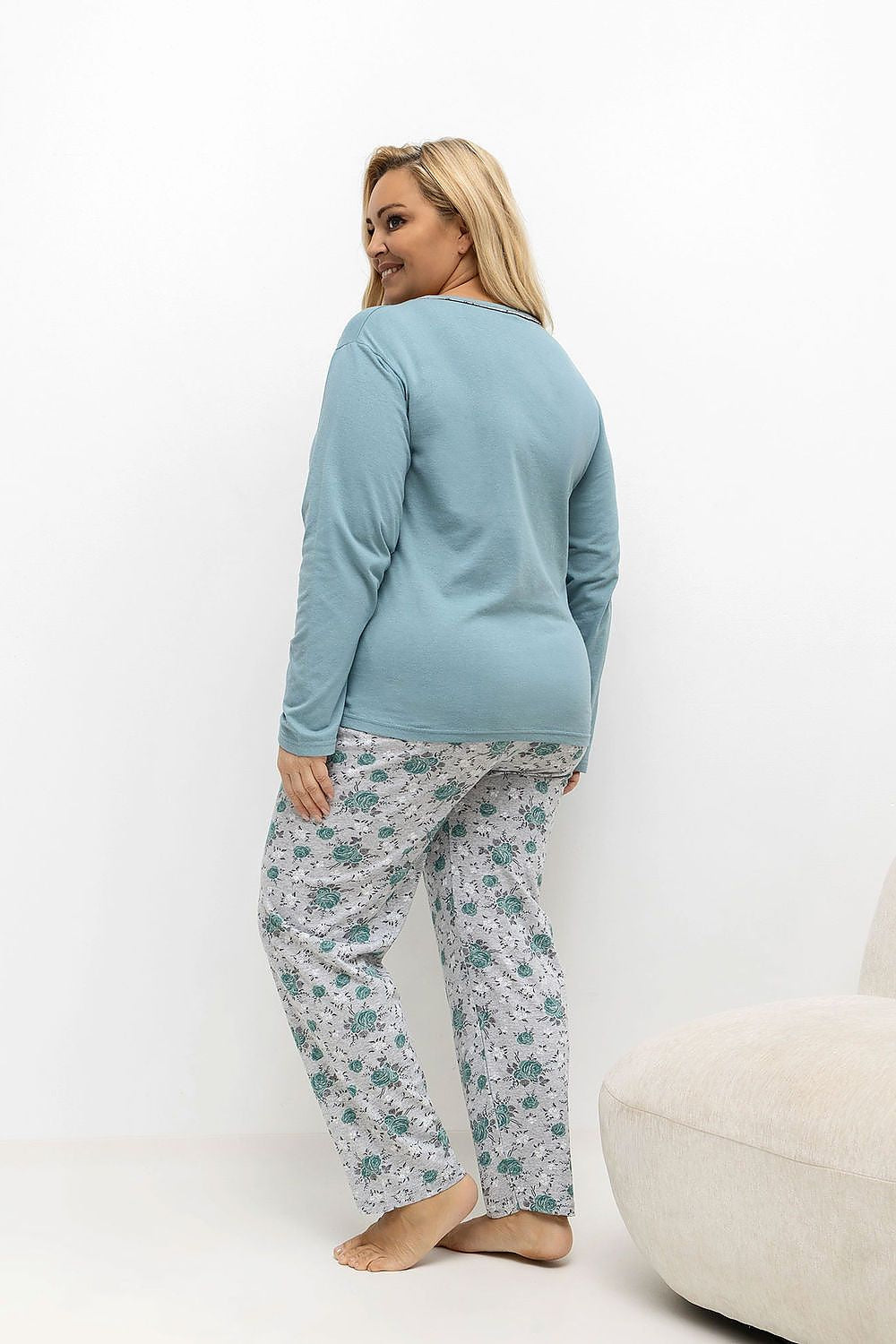 Woman wearing a blue top and floral pants on a white background