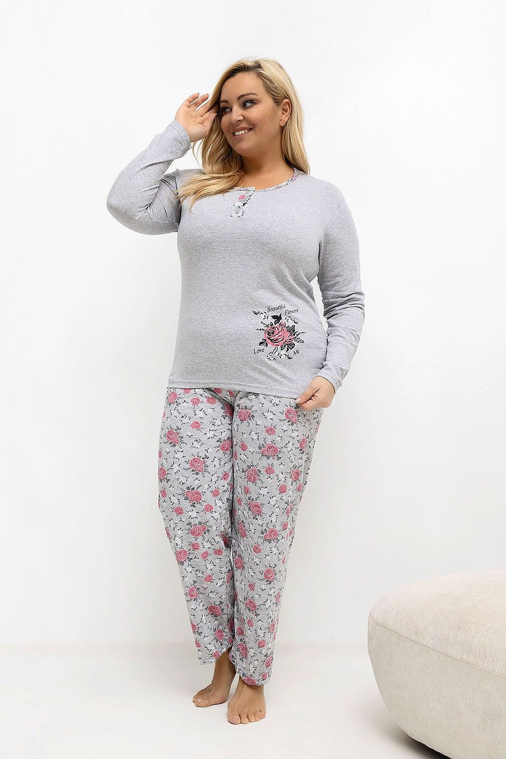 Woman wearing a gray long-sleeve top and floral pajama pants on a white background