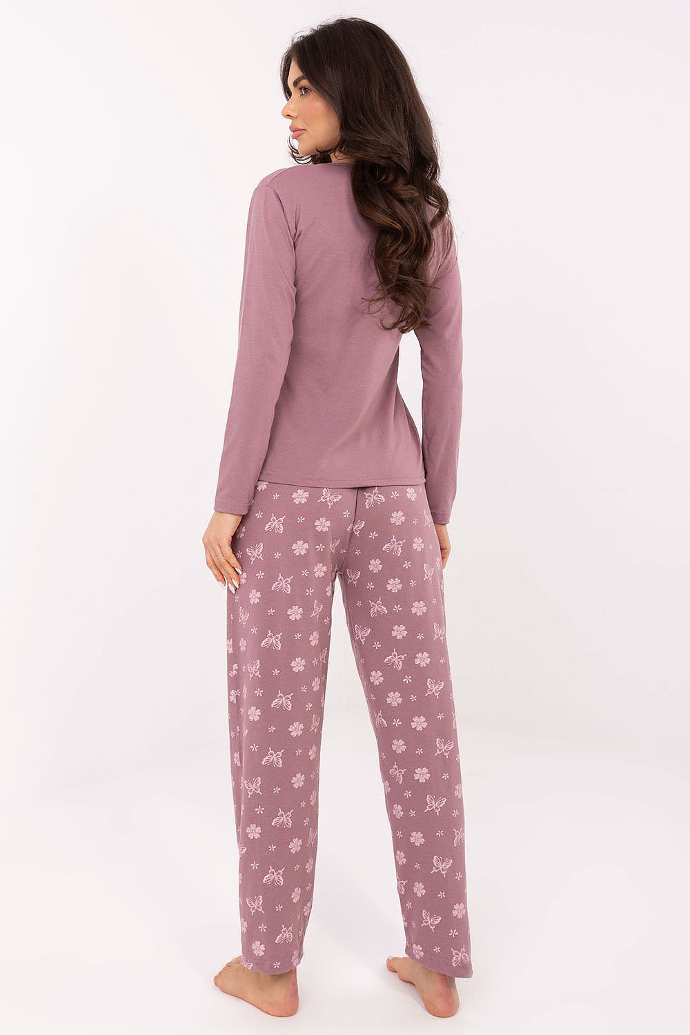 Woman wearing a pink pajama set with floral pattern on pants against a white background