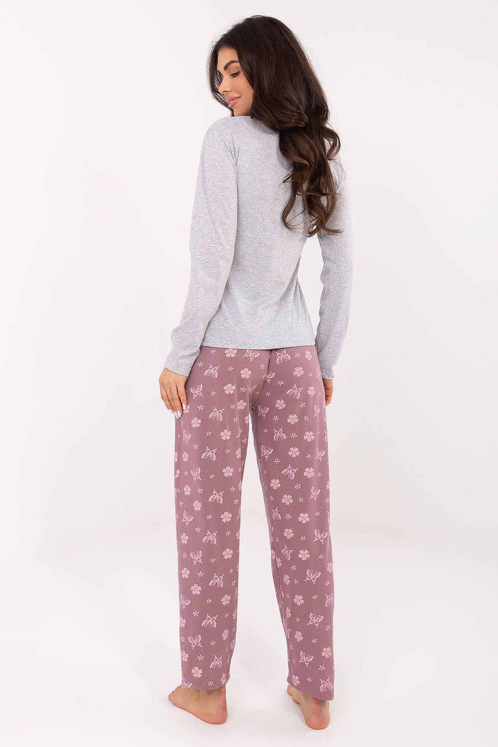 Woman wearing a gray long-sleeve top and pink floral pajama pants on a white background