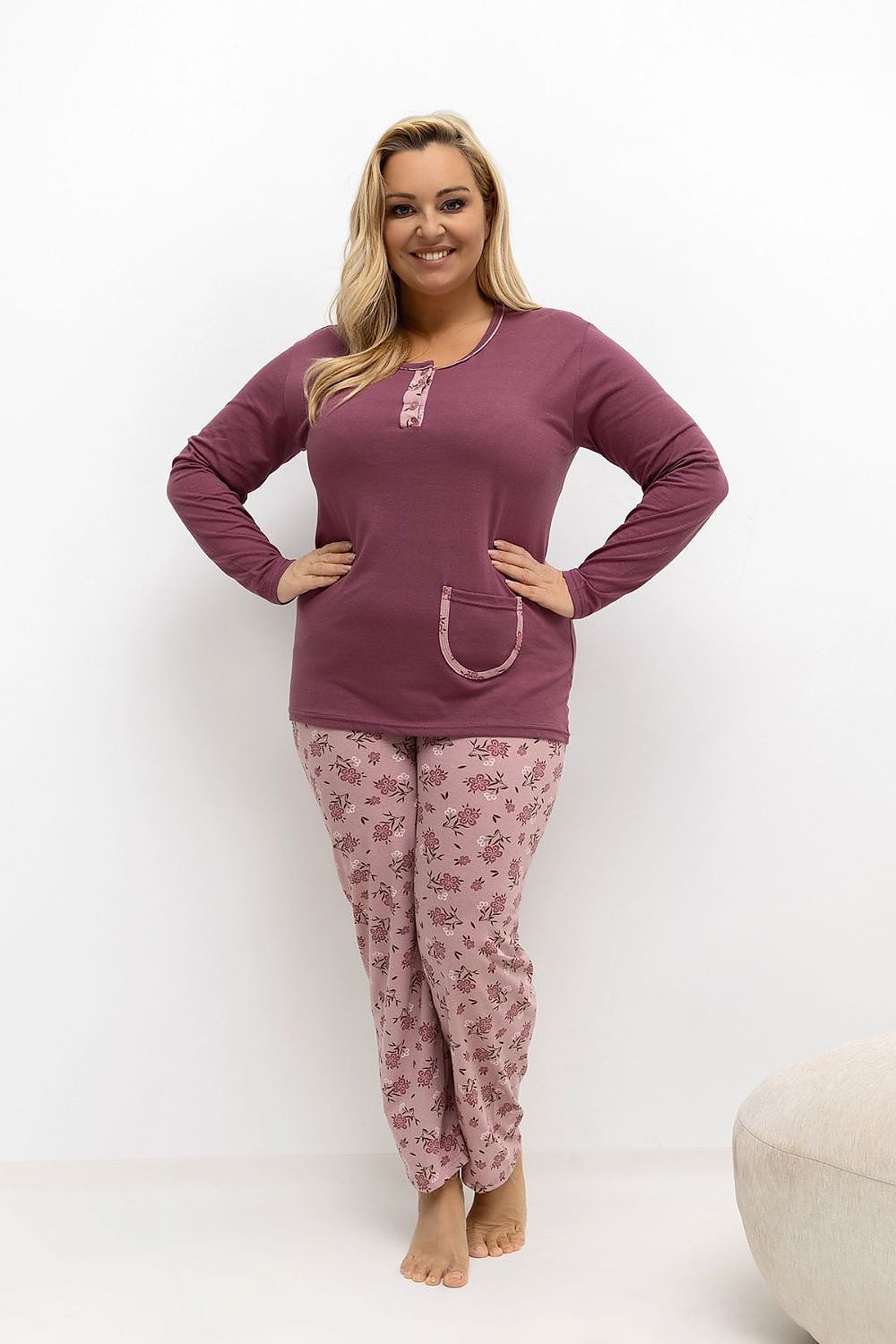 Woman wearing a matching purple pajama set with floral pants on a white background