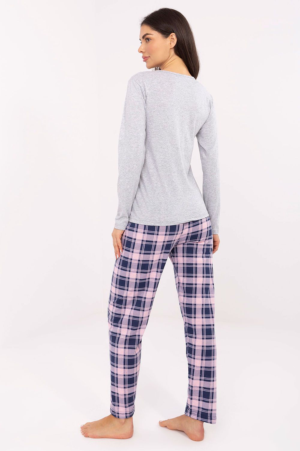 Woman wearing a gray long-sleeve top and pink plaid pants on a white background