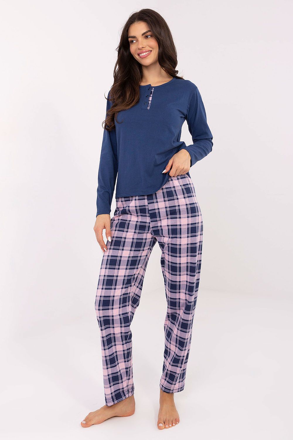 Woman wearing a blue long-sleeve top and plaid pants on a white background