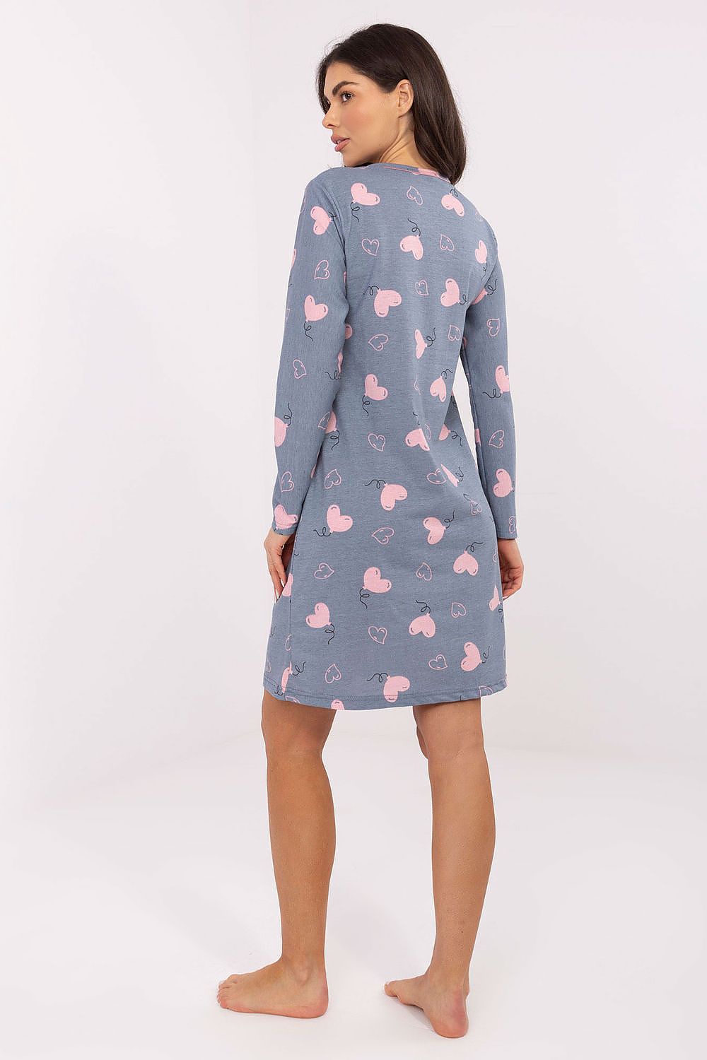 Woman wearing a blue nightgown with pink heart patterns on a white background