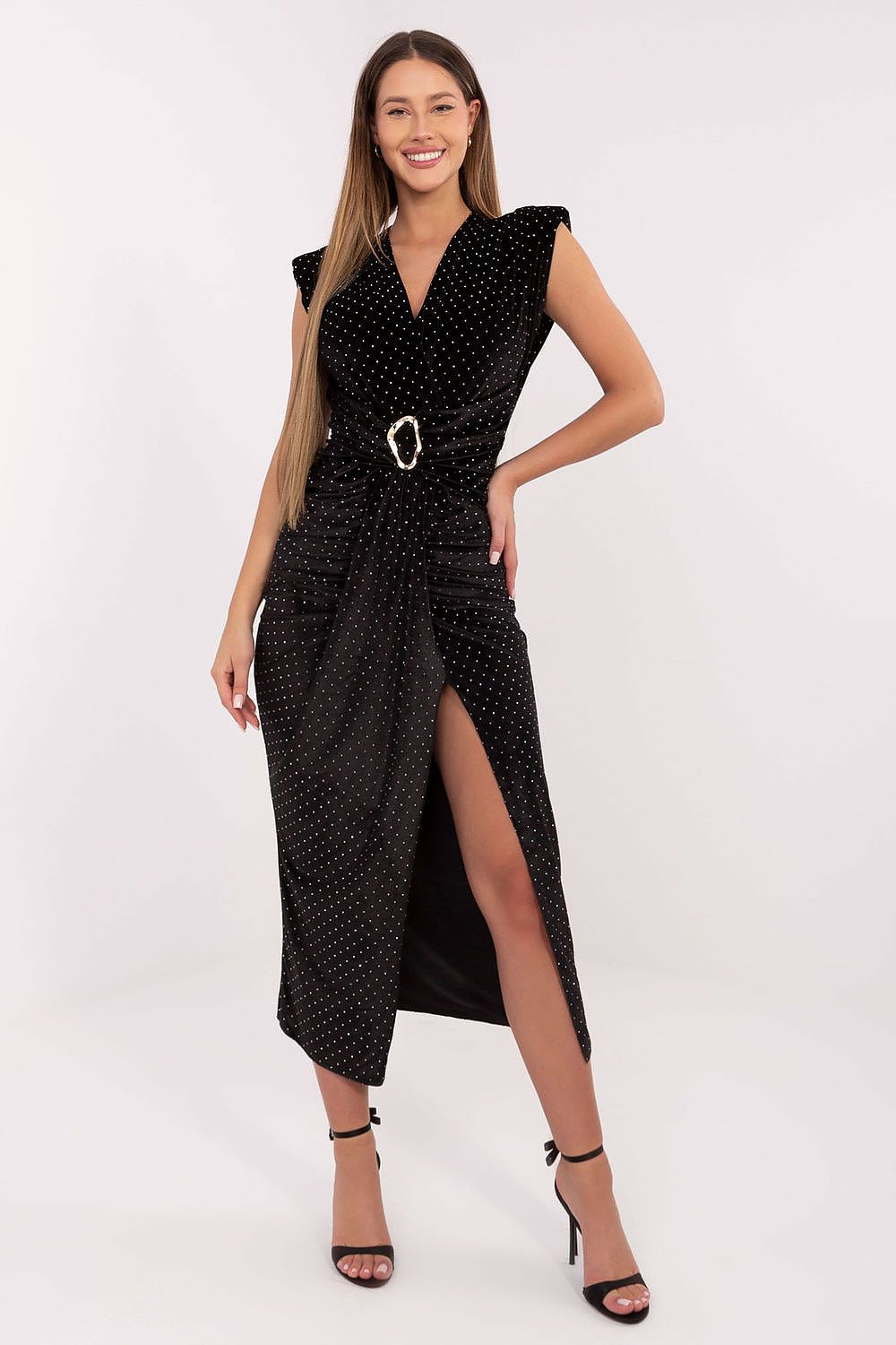 Woman wearing a black polka dot dress with a belt on a white background